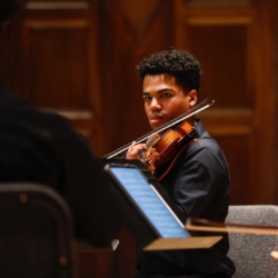 网赌论坛有哪些 student plays the violin during a concert.